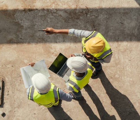 Dev1 Top view, Team engineer building inspection use tablet computer and blueprint working at construction site. Civil Engineer, Contractor and Architect discussing in construction site.