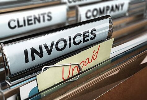 Close up on a file tab with the word invoice and a note where it is handwritten unpaid with blur effect. Concept image for illustration of unpaid invoices recovery.