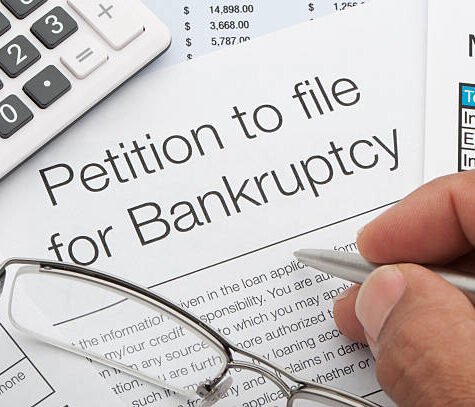 Close up of bankruptcy petition with calculator and writing hand