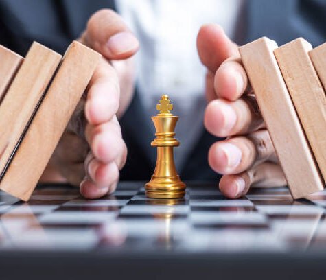 Business man hand protect Chess King figure and Stopping Falling wooden Blocks or Dominoes. Business, Risk Management, Solution, economic regression, Insurance, strategy and Interruption Concepts